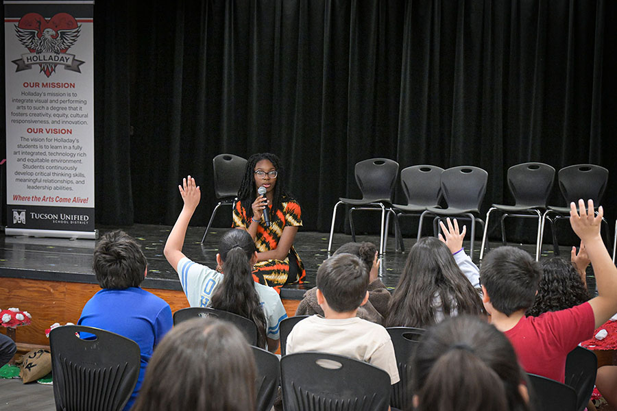 A teen girl addresses students' questions in the auditorium