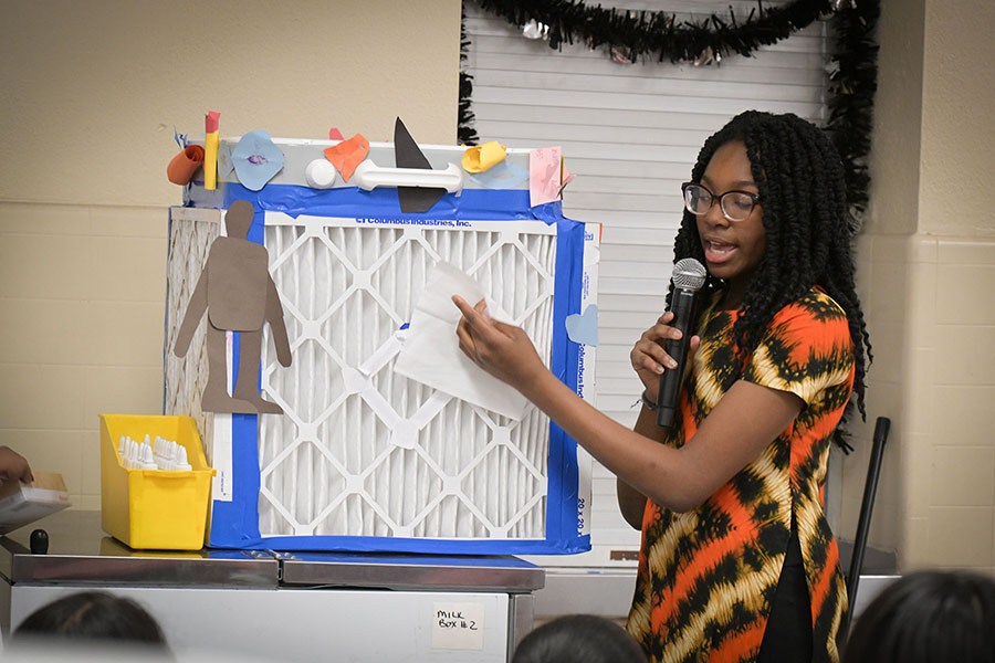 A teen girl shows the air filter she invented