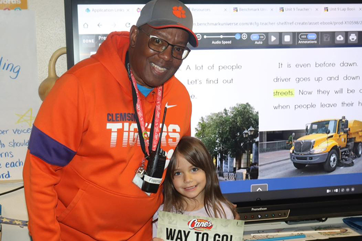 A man in an orange hoodie smiles with a little girl holding a Way to Go certificate