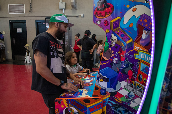 A dad and son play an arcade game together