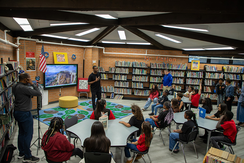 A man talks to a group of students in the library