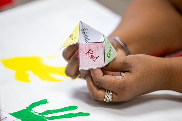 A woman holds up a colorful paper fortune teller