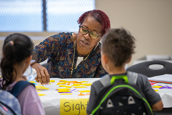A woman talks to a young girl and boy