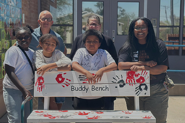 Three students and three administrators gather around the Buddy Bench