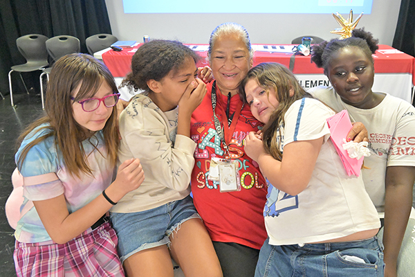 A woman in a red shirt gets hugs from four girls
